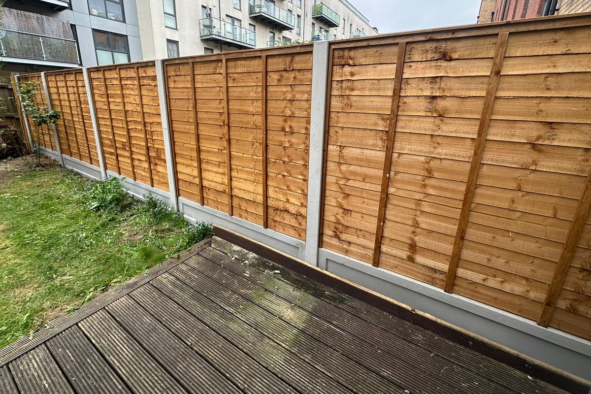 The same boundary after work: new lap panels on concrete posts and gravel boards