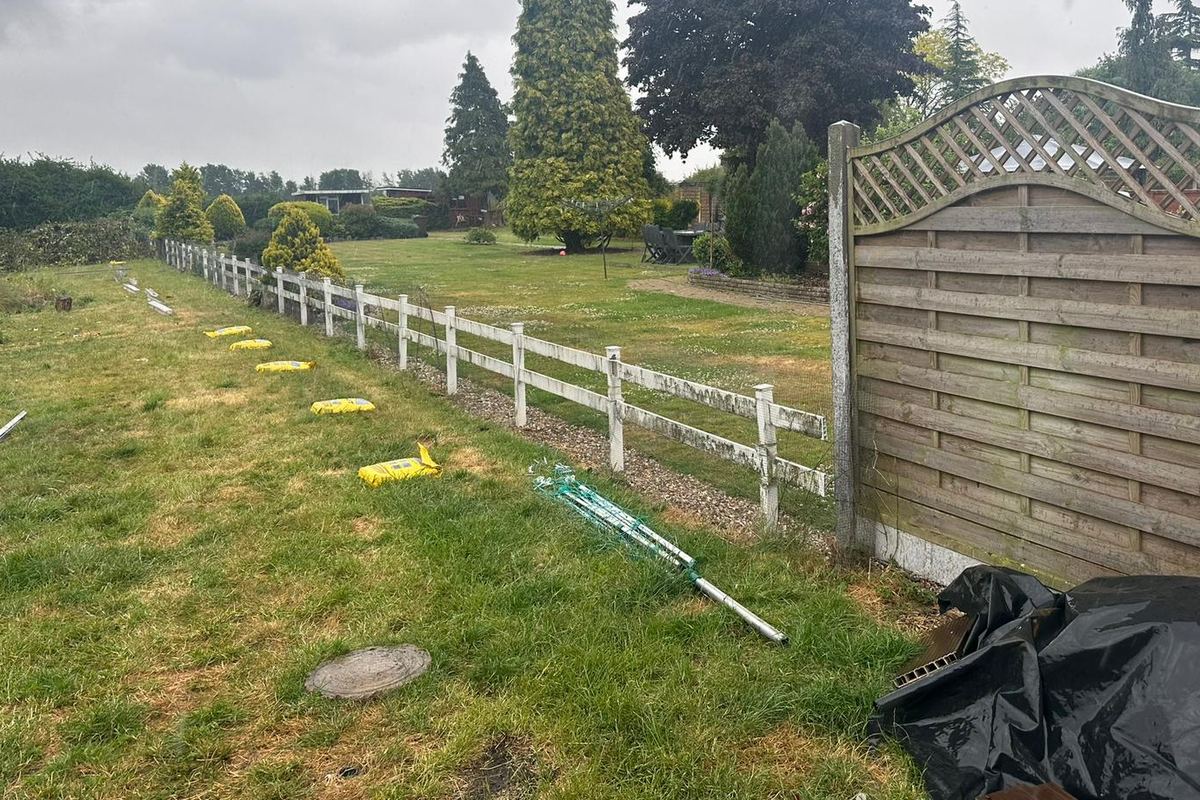 The same boundary before work: an old white post-and-rail fence along the garden edge