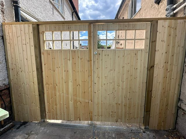 A pair of new timber side gates with window-style openings in the top rails