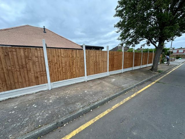 A run of new closeboard fencing along a roadside boundary beside a bungalow