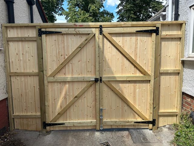 The braced inside face of a pair of new timber gates, with black strap hinges