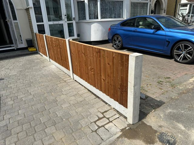A low run of closeboard fencing on concrete posts dividing a front driveway