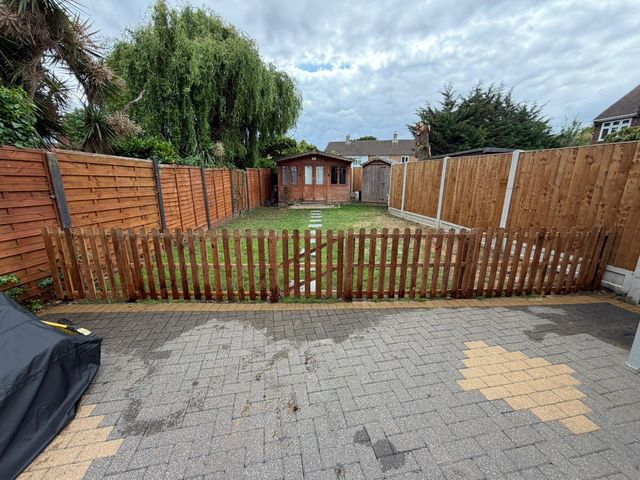 New picket fencing with a matching gate between a paved yard and a lawn