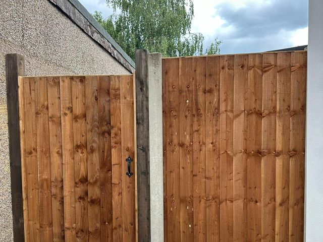 A closeboard side gate next to a closeboard panel on a concrete post