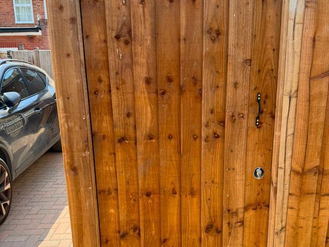 A new closeboard side gate with a ring latch beside a block-paved driveway
