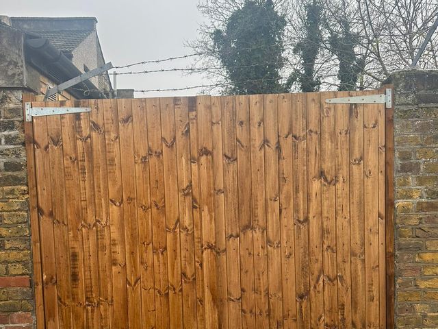 A pair of closeboard gates on galvanised hinges set into an old brick wall
